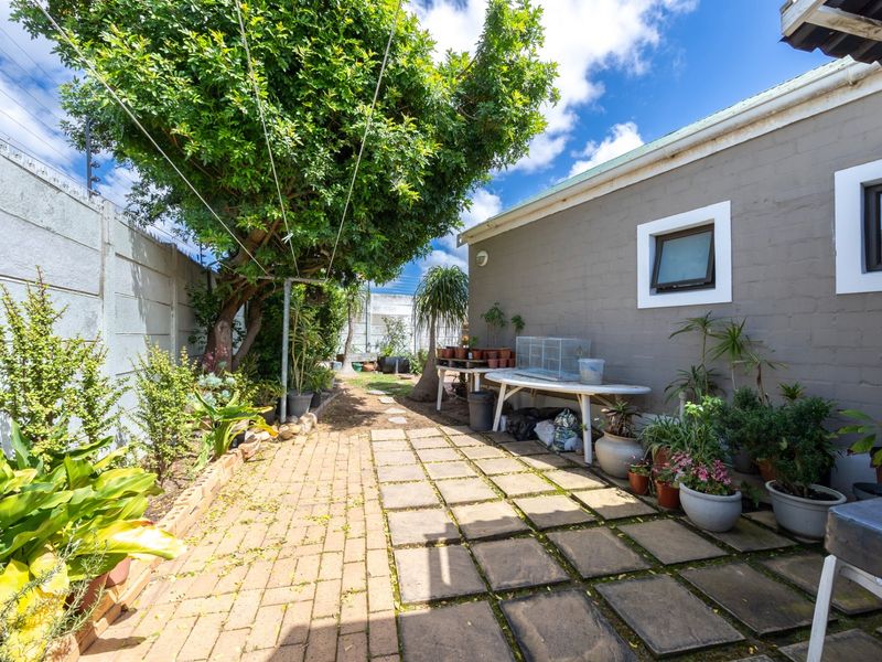 A rear garden area featuring a paved patio, precast boundary walling, and established greenery, offering a functional outdoor space for the property.
