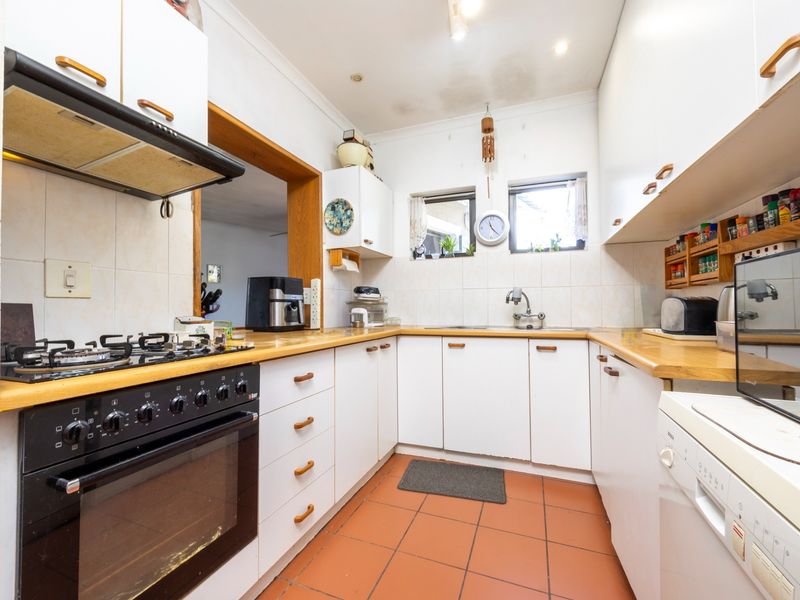 A functional kitchen featuring white cabinetry, gas hob, built-in oven, tiled flooring, and a double sink with tiled backsplash.