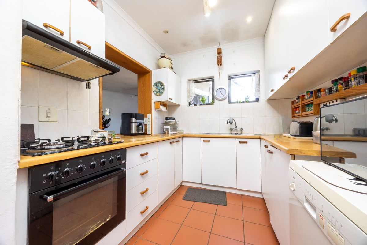 A functional kitchen featuring white cabinetry, gas hob, built-in oven, tiled flooring, and a double sink with tiled backsplash.