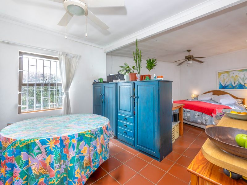 A bedroom featuring tiled flooring, ceiling fans, and security bars on the window, offering a functional layout with potential for modernization.