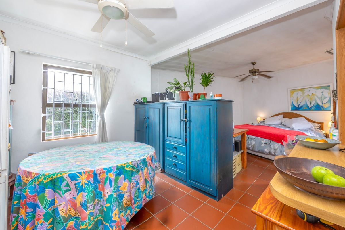 A bedroom featuring tiled flooring, ceiling fans, and security bars on the window, offering a functional layout with potential for modernization.