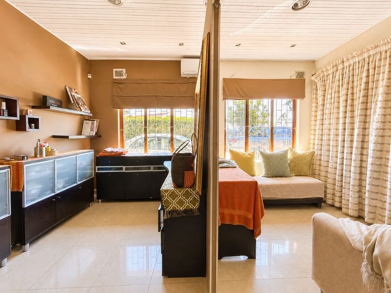 A living area featuring tiled floors, a timber ceiling with recessed lighting, and a split-system air conditioner, divided by a central partition wall.