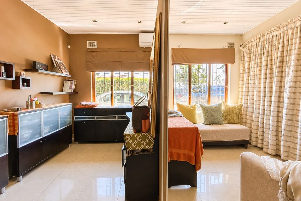 A living area featuring tiled floors, a timber ceiling with recessed lighting, and a split-system air conditioner, divided by a central partition wall.