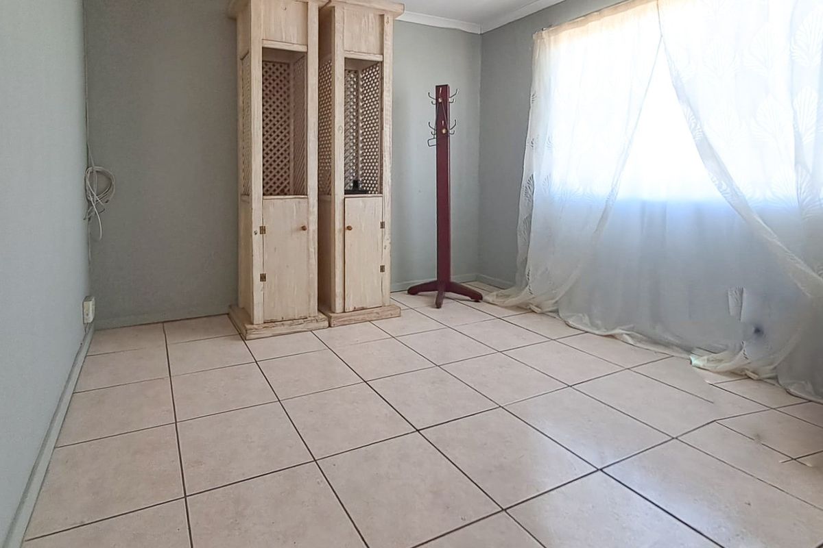 A vacant bedroom featuring neutral wall tones and tiled flooring, offering a blank canvas for personalization.