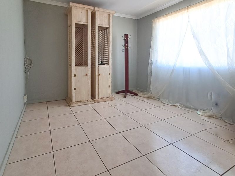 A vacant bedroom featuring neutral wall tones and tiled flooring, offering a blank canvas for personalization.