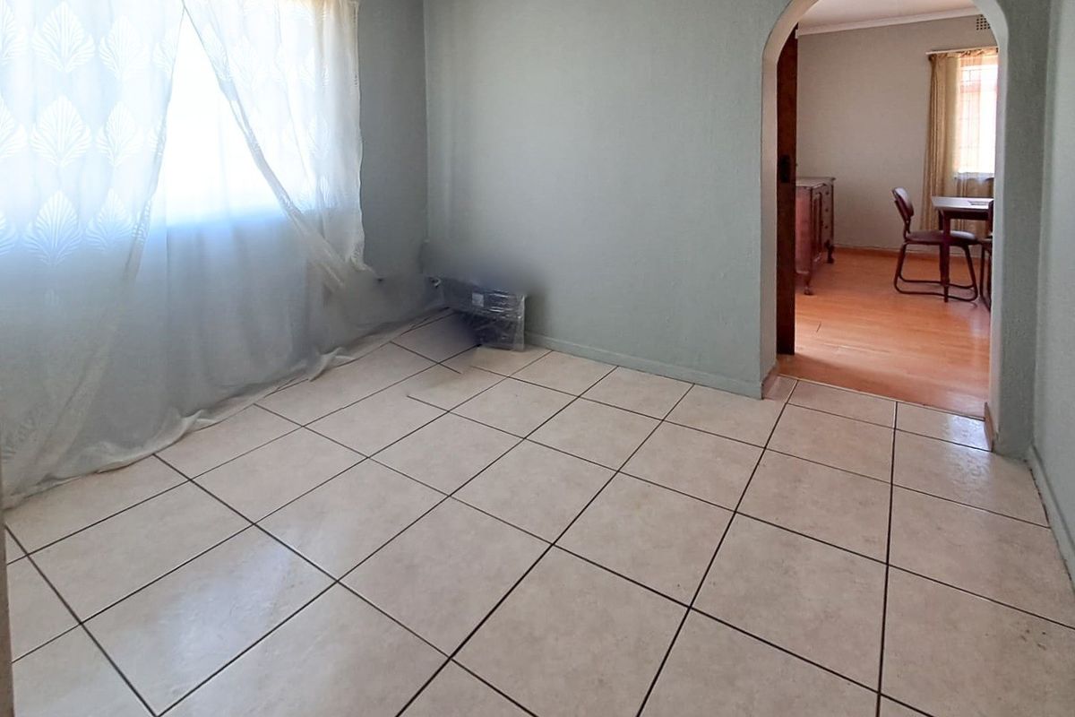 An empty living room featuring neutral tiled flooring and a classic arched doorway leading to an adjacent space.