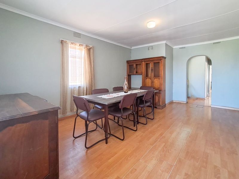 A dining room featuring laminate flooring and an arched entryway, providing a functional space with neutral wall tones.