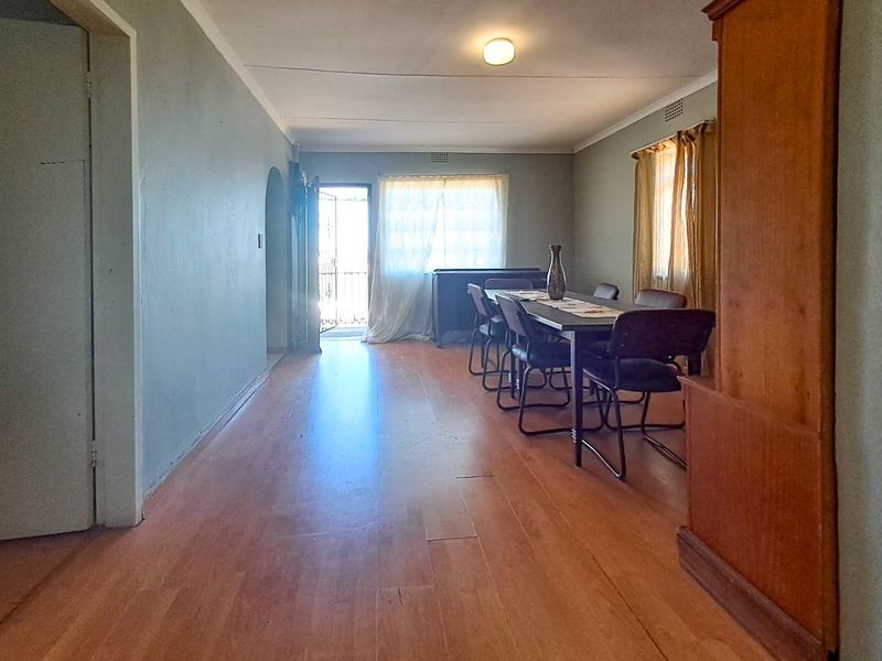 A dining room featuring laminate flooring and coved ceilings, offering a functional space with direct access to the exterior through a security gate.