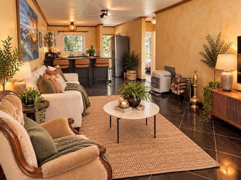 An open-plan living and kitchen area featuring dark tiled flooring, a kitchen island with breakfast bar seating, and warm-toned wall finishes.