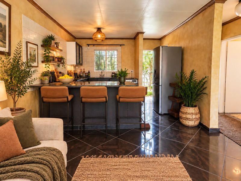 Open-plan kitchen and living area featuring a central island with stone countertops, dark cabinetry, and polished tiled flooring, creating a warm and inviting space.