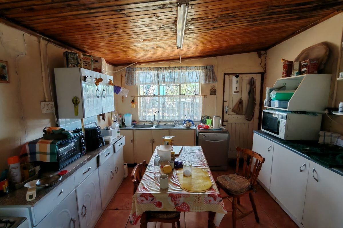 A functional kitchen featuring built-in cabinetry, a double basin sink, and a traditional wooden tongue and groove ceiling with tiled flooring.
