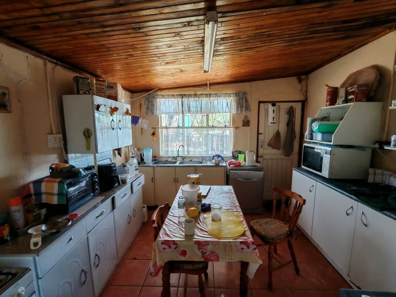 A functional kitchen featuring built-in cabinetry, a double basin sink, and a traditional wooden tongue and groove ceiling with tiled flooring.