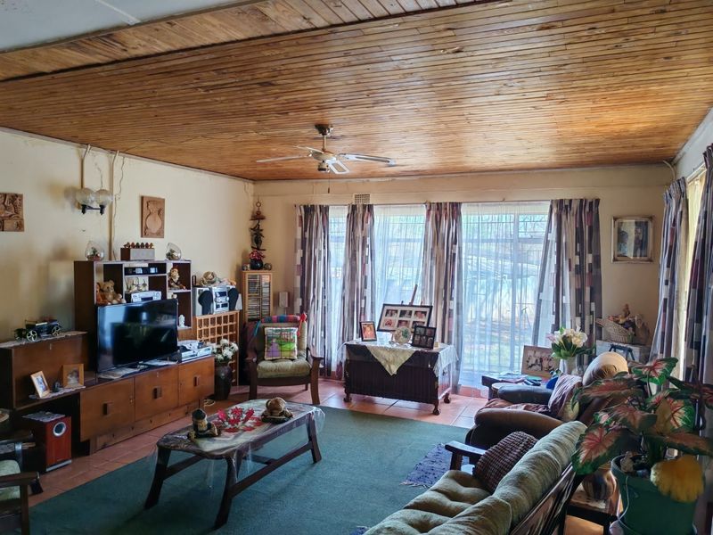 Spacious living room featuring a warm timber tongue and groove ceiling, tiled flooring, and large sliding doors that provide ample natural light.