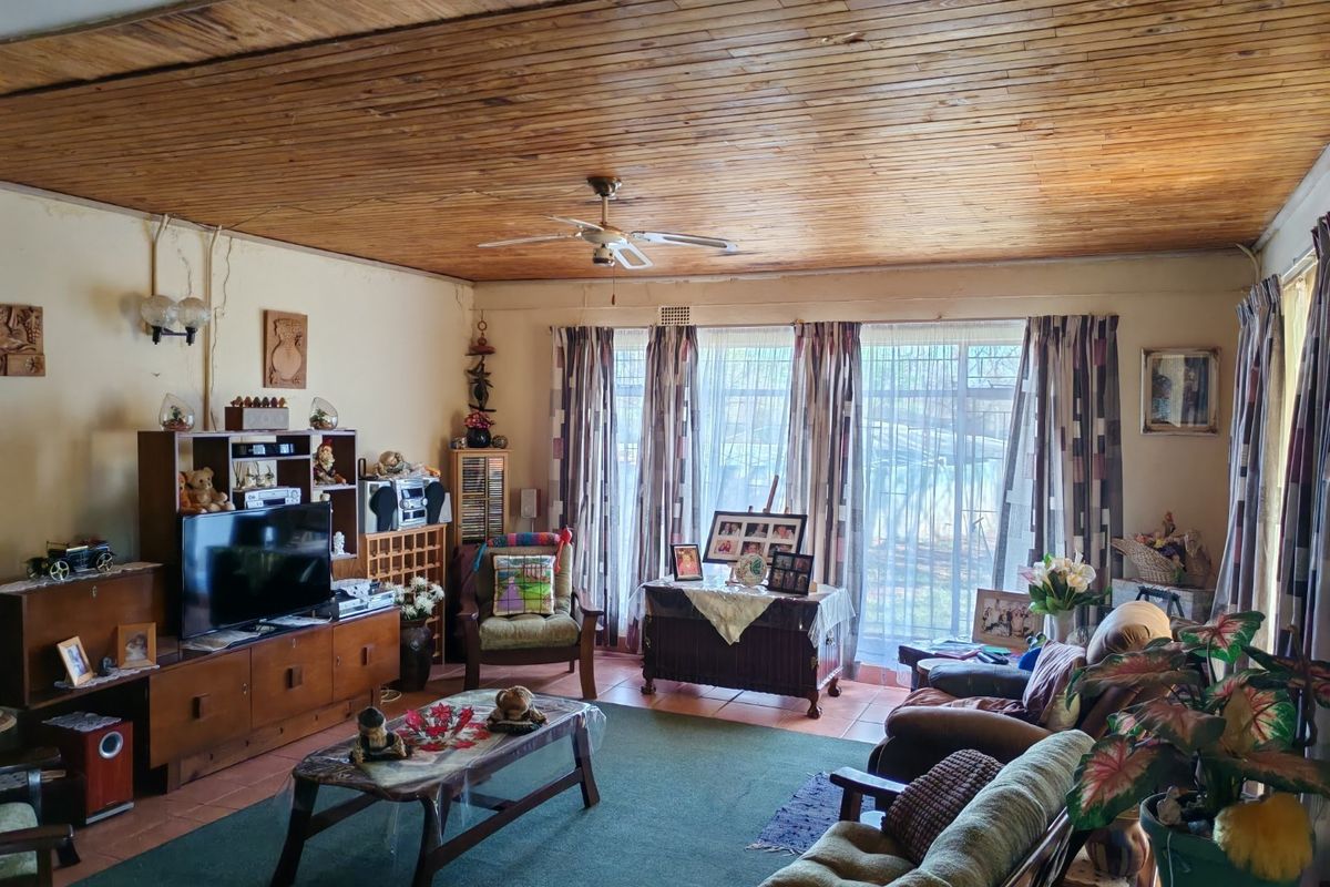 Spacious living room featuring a warm timber tongue and groove ceiling, tiled flooring, and large sliding doors that provide ample natural light.