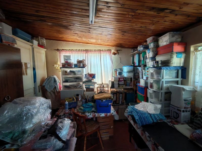 A utility or storage room featuring a timber tongue and groove ceiling and built-in cupboard storage, currently used for general storage.