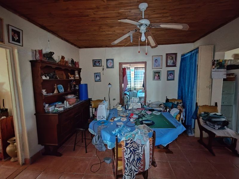Living area featuring a timber ceiling, ceiling fan, and terracotta floor tiles, currently utilized as a multi-purpose workspace.