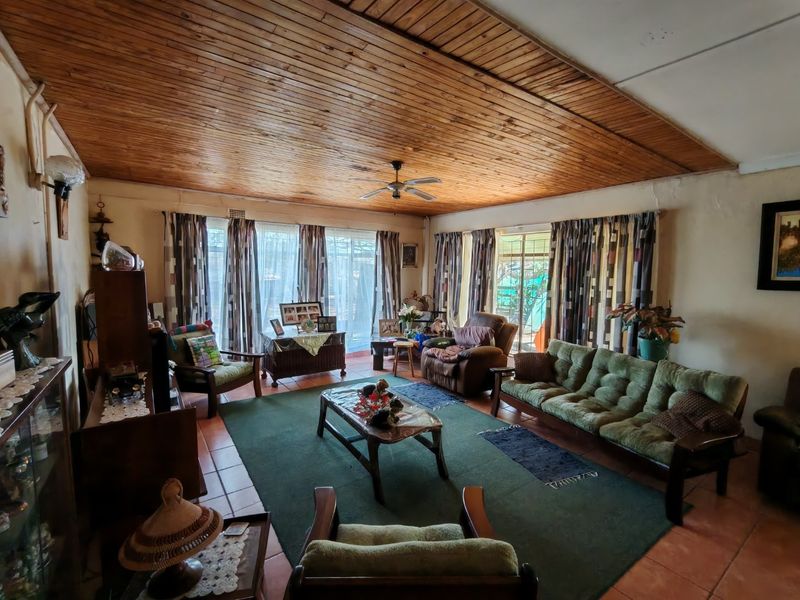 Spacious living room featuring a warm wooden tongue and groove ceiling, tiled flooring, and large sliding glass doors providing access to the outdoor area.