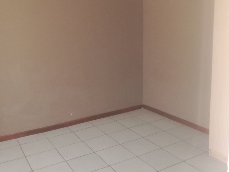 A clean, empty bedroom featuring neutral wall tones, tiled flooring, and coved ceiling detailing, providing a versatile space ready for personalization.