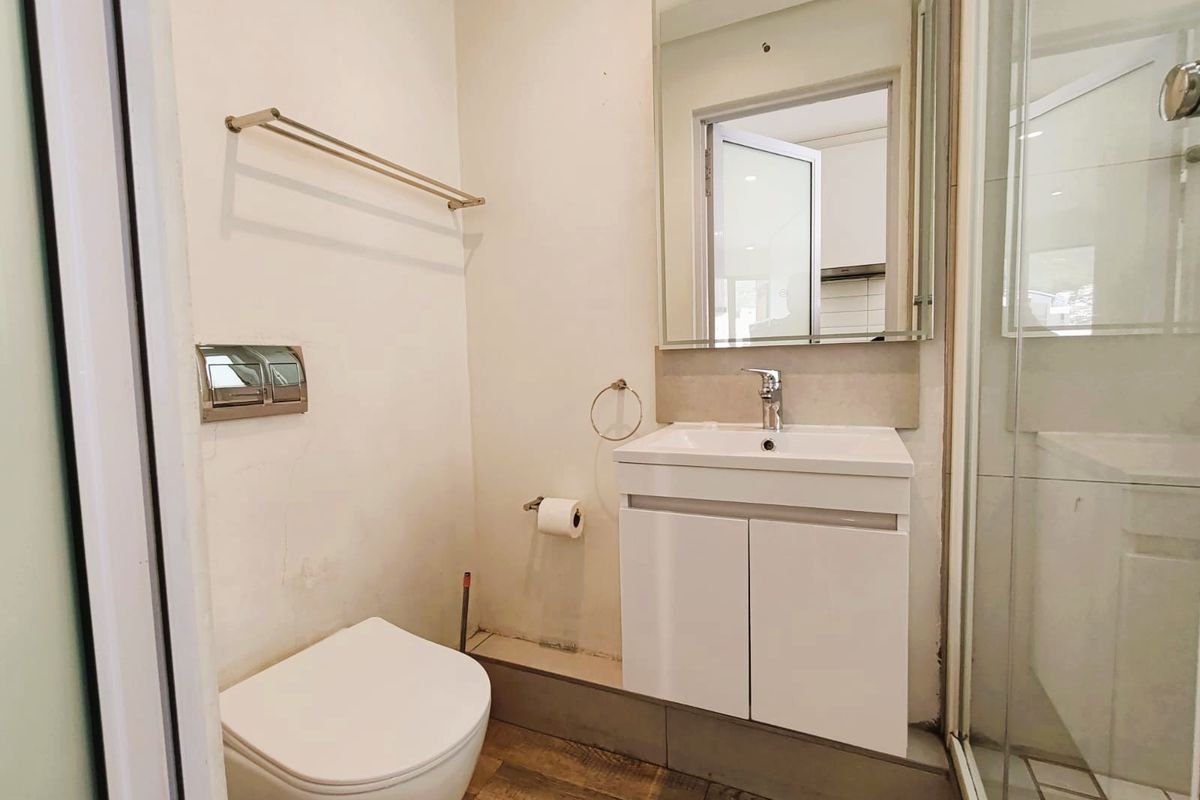 Compact bathroom featuring a modern vanity, wall-mounted toilet, and a glass-enclosed shower with contemporary fixtures.