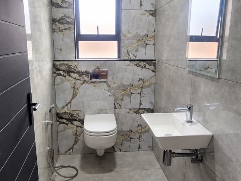 Modern, compact bathroom featuring floor-to-ceiling marble-effect tiling, a wall-mounted basin, and a wall-hung toilet with contemporary chrome fixtures.