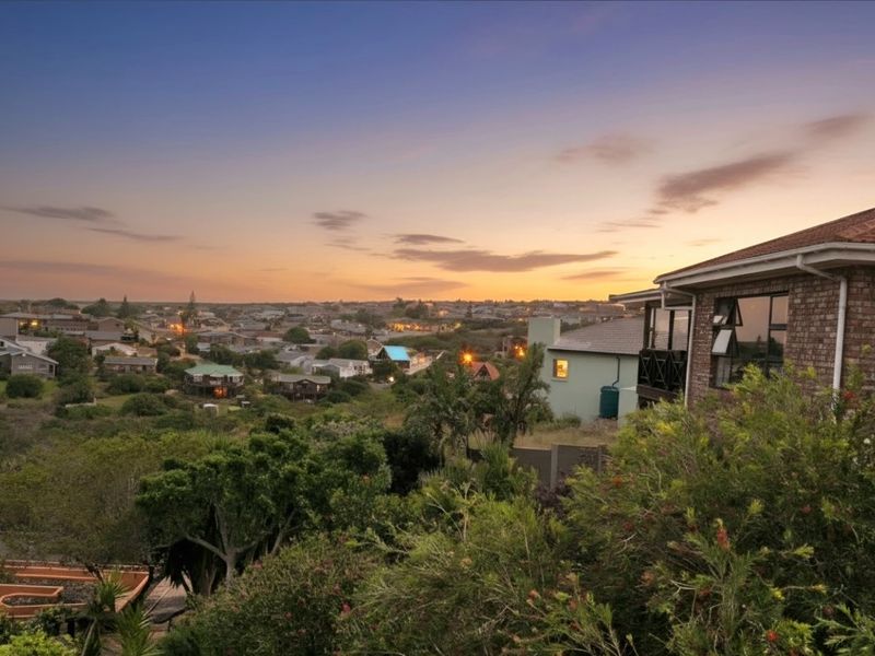 A scenic elevated view overlooking the surrounding residential neighbourhood at sunset, featuring the side profile of a brick-clad house.