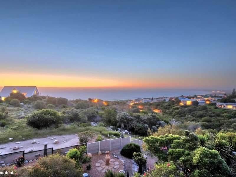 A scenic elevated view overlooking a coastal landscape and residential area at sunset.