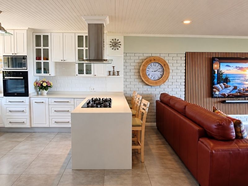Spacious open-plan kitchen and living area featuring a central island with gas hob, modern cabinetry, and stylish wood-paneled feature wall.