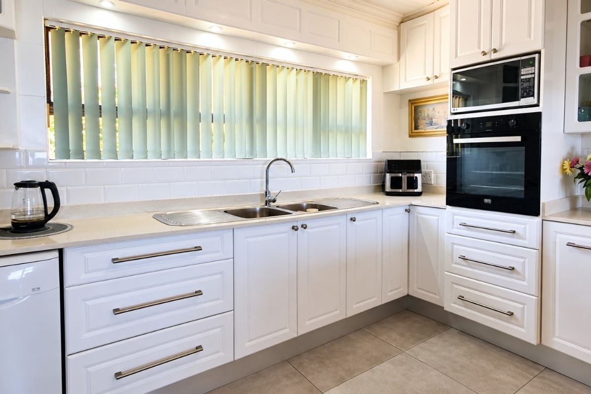 A well-maintained kitchen featuring white shaker-style cabinetry, stone countertops, a subway tile backsplash, and integrated appliances including an oven and microwave.