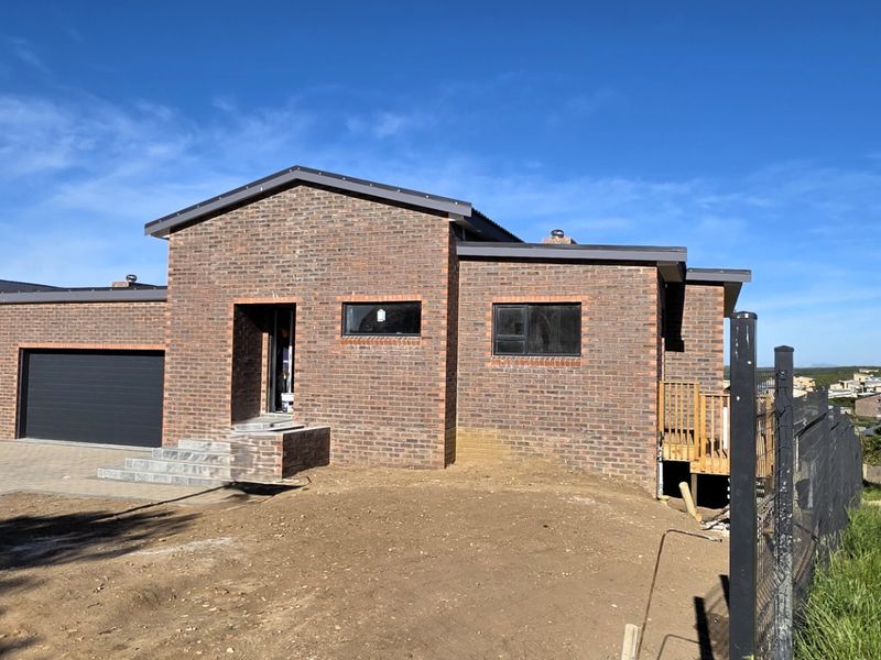 Modern face brick house featuring a double garage, paved driveway, and a timber deck, currently undergoing final exterior landscaping.