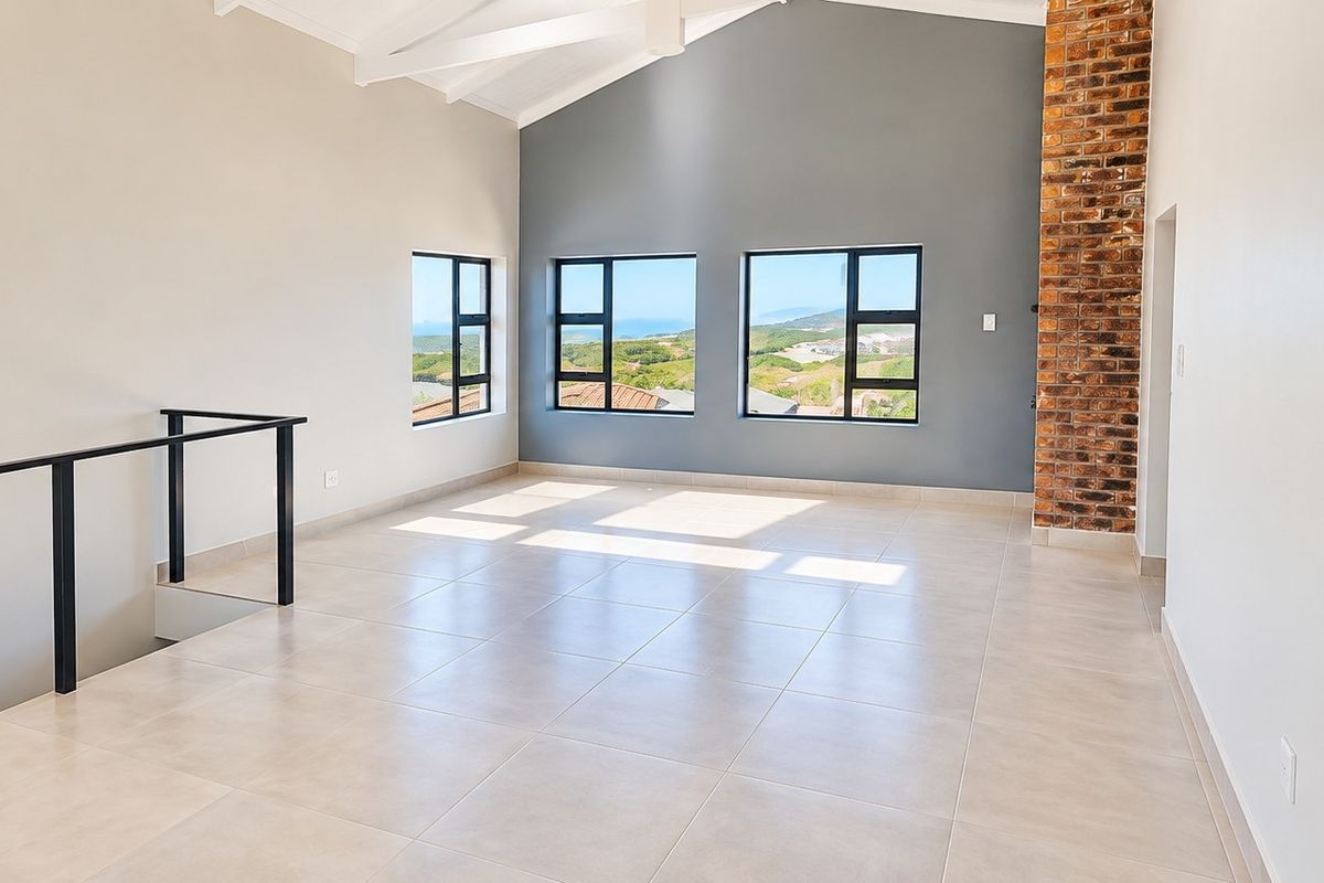 Spacious open-plan living area featuring a vaulted ceiling, tiled floors, and a striking exposed brick chimney breast with scenic views.