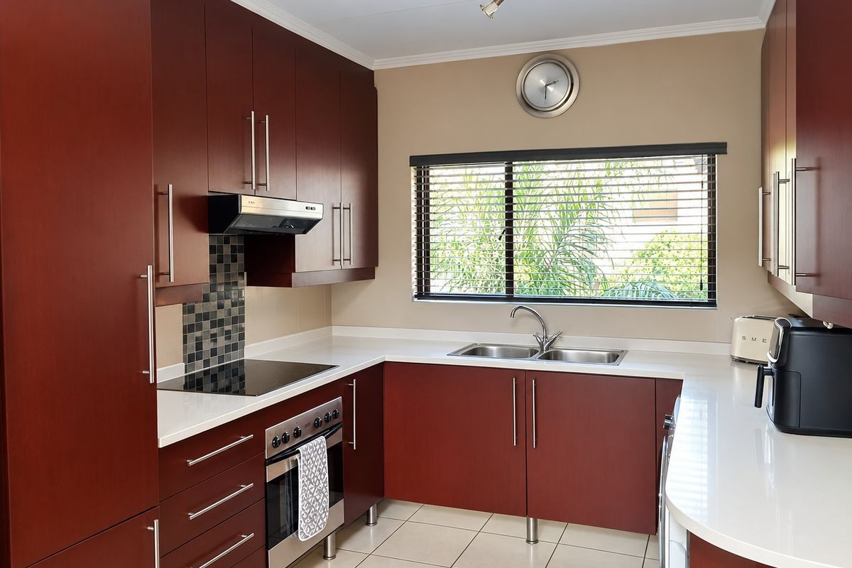 A well-maintained kitchen featuring dark wood cabinetry, stone countertops, integrated appliances, and a tiled backsplash, offering a clean and functional workspace.