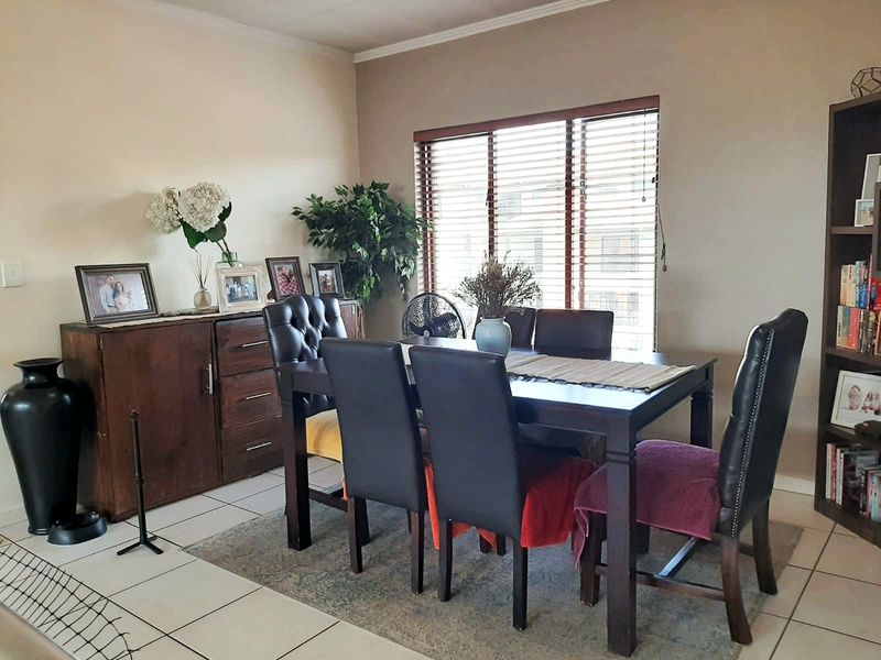 A dining room featuring tiled flooring, venetian blinds, and a built-in shelving unit, providing a functional space for meals and storage.