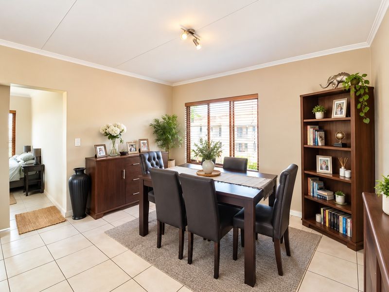 A well-maintained dining room featuring neutral wall tones, tiled flooring, and natural light filtered through venetian blinds.