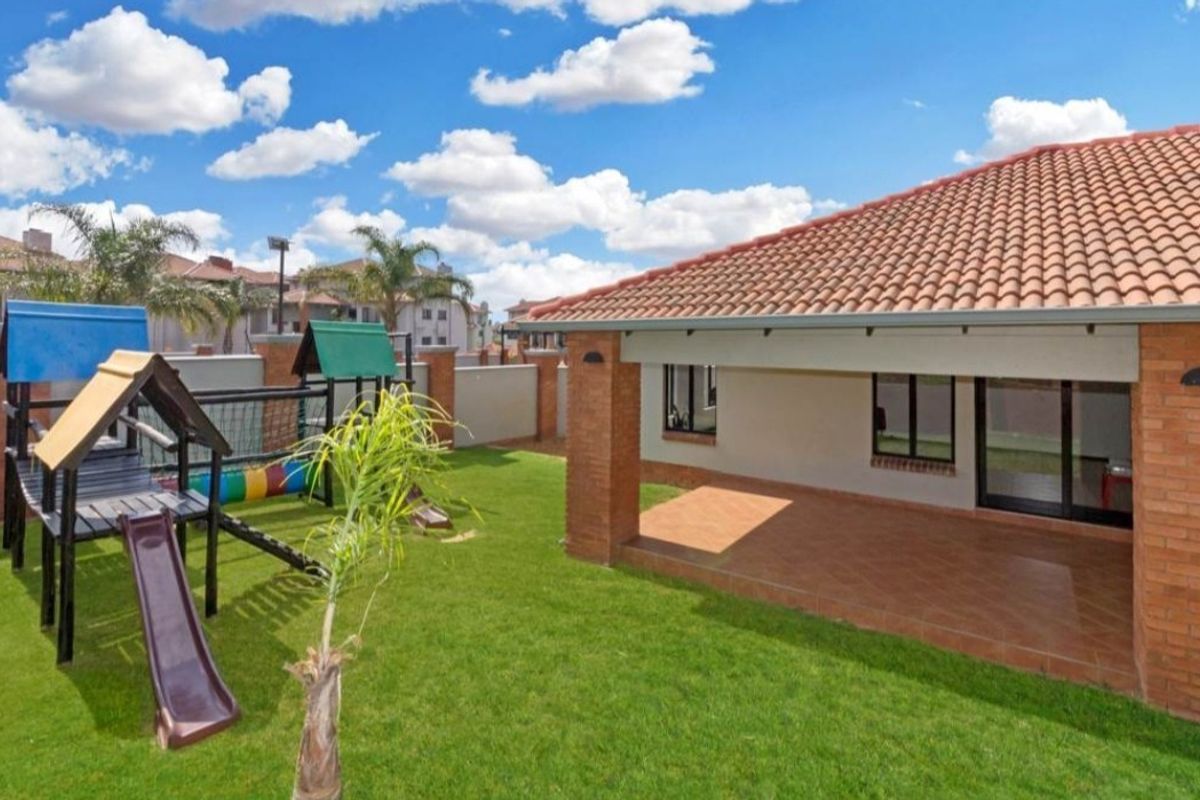 A well-maintained rear garden featuring a covered tiled patio, brick pillars, and a neat lawn area, perfect for outdoor relaxation.