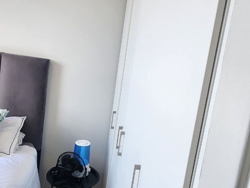 A bedroom featuring modern built-in cupboards and laminate flooring, providing clean and functional storage space.