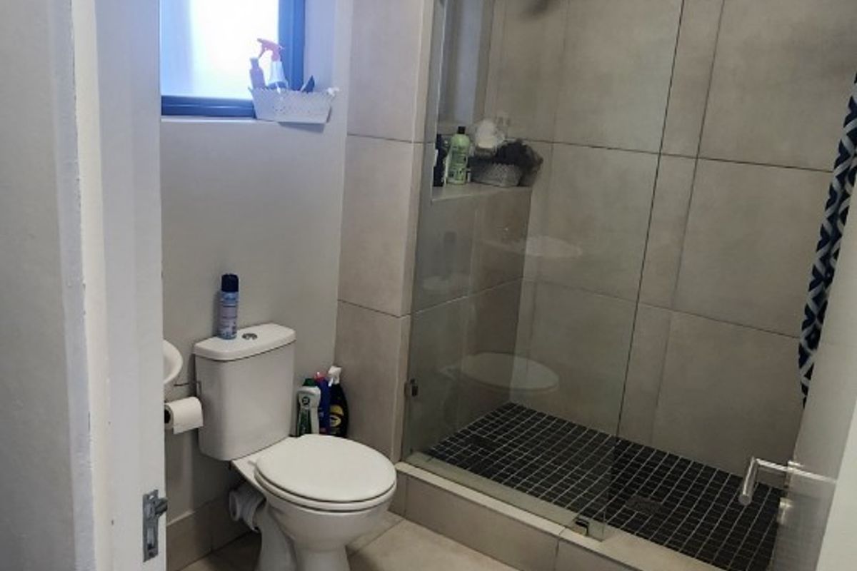 A functional bathroom featuring a walk-in shower with a glass screen, tiled flooring, and a standard toilet.