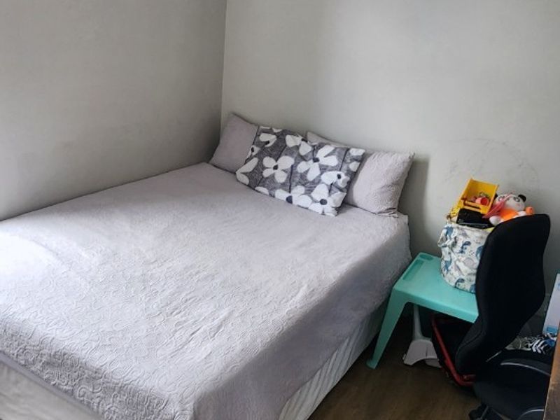 A compact bedroom featuring durable laminate flooring and neutral wall finishes, offering a functional space ready for personalization.