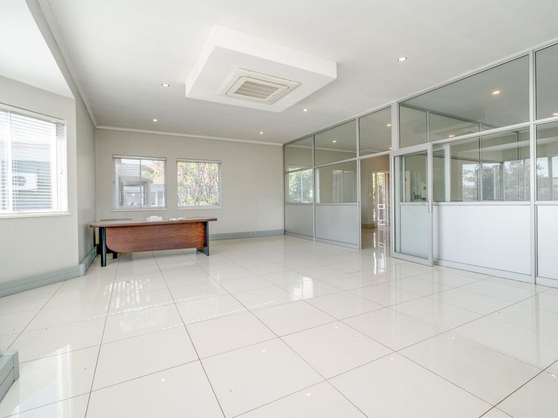 A bright, open-plan office space featuring polished tiled flooring, modern aluminium-framed glass partitioning, and integrated ceiling air conditioning.