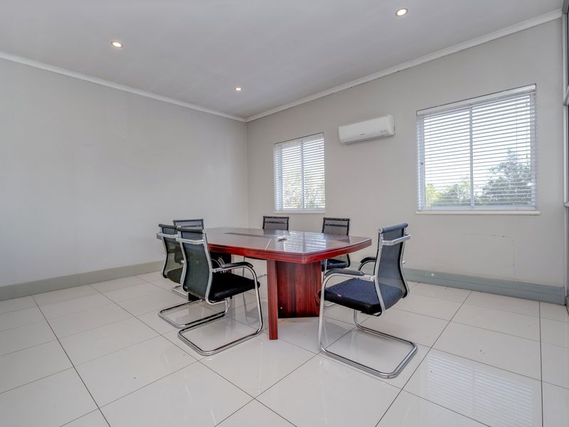 A professional office space featuring tiled flooring, recessed lighting, and a wall-mounted air conditioning unit, providing a clean and functional work environment.