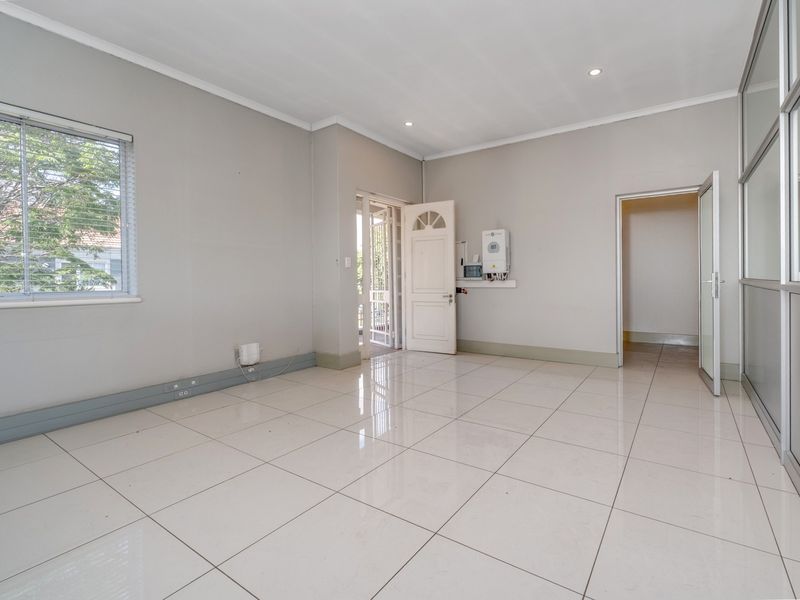 A bright, empty office space featuring polished tiled flooring, recessed lighting, and a modern aluminium partition wall, suitable for a professional workspace.