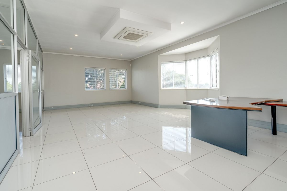 A bright and spacious open-plan office area featuring polished tiled floors, recessed ceiling lighting, integrated air conditioning, and large windows with aluminium frames.
