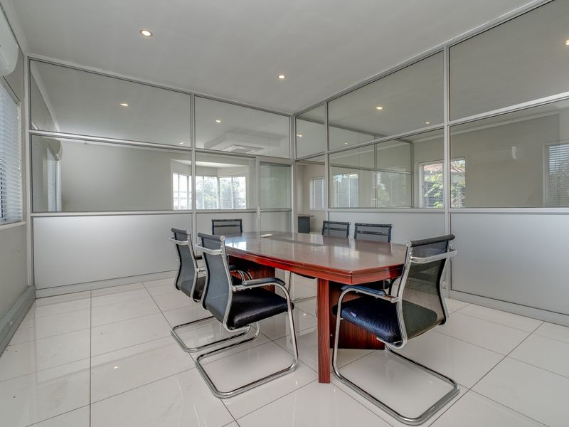 A professional office meeting room featuring modern aluminium and glass partitioning, tiled flooring, recessed lighting, and integrated air conditioning.
