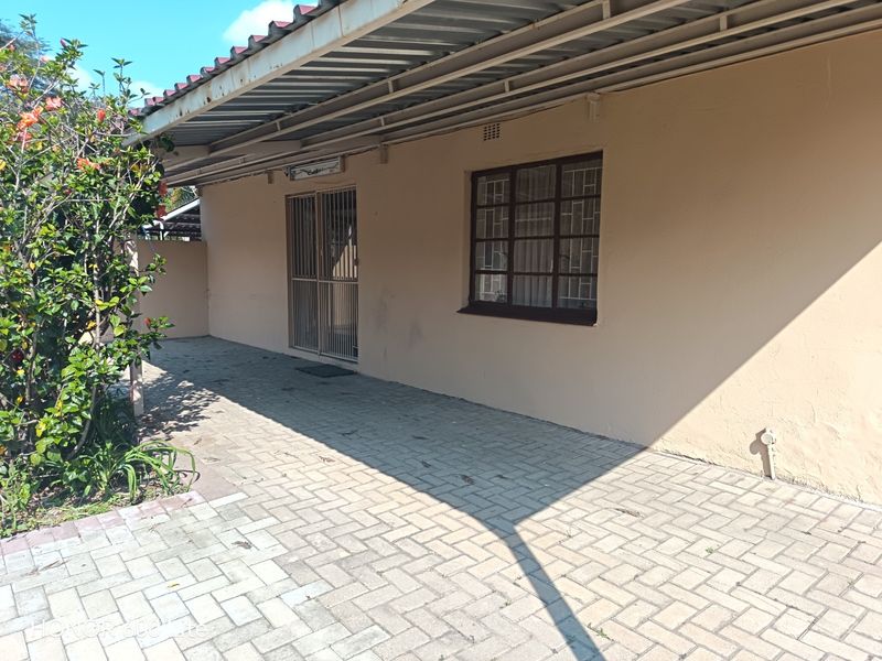 A covered patio area featuring paved flooring, security gate, and window security bars, providing a functional outdoor space for the apartment.