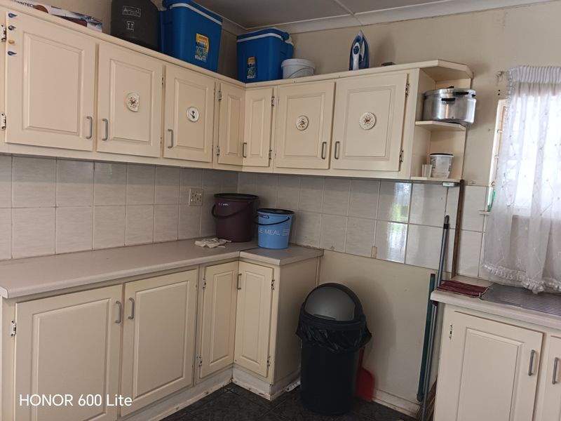 A dated kitchen featuring cream-colored cabinetry, laminate countertops, and a tiled backsplash, offering a functional layout ready for modernization and cosmetic updates.