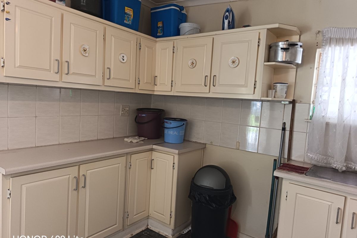 A dated kitchen featuring cream-colored cabinetry, laminate countertops, and a tiled backsplash, offering a functional layout ready for modernization and cosmetic updates.