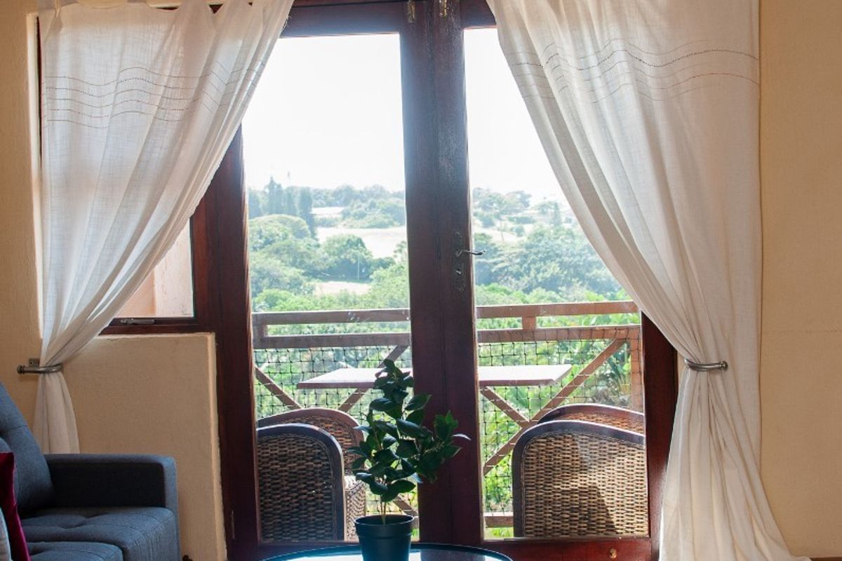 A well-lit bedroom featuring tiled flooring, recessed downlights, and double glass doors opening onto a balcony with scenic views.