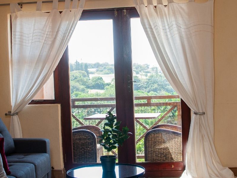 A well-lit bedroom featuring tiled flooring, recessed downlights, and double glass doors opening onto a balcony with scenic views.