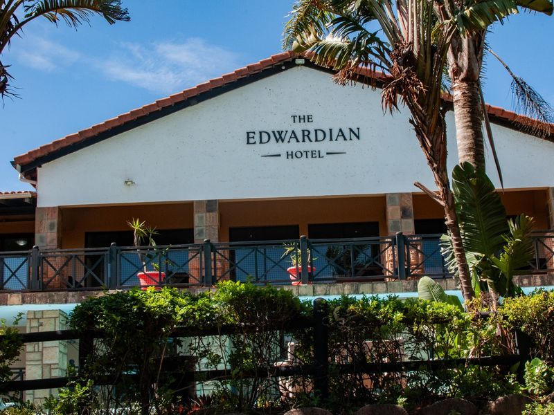 Front elevation of The Edwardian Hotel building featuring a tiled roof, stone-clad pillars, and a covered balcony area.