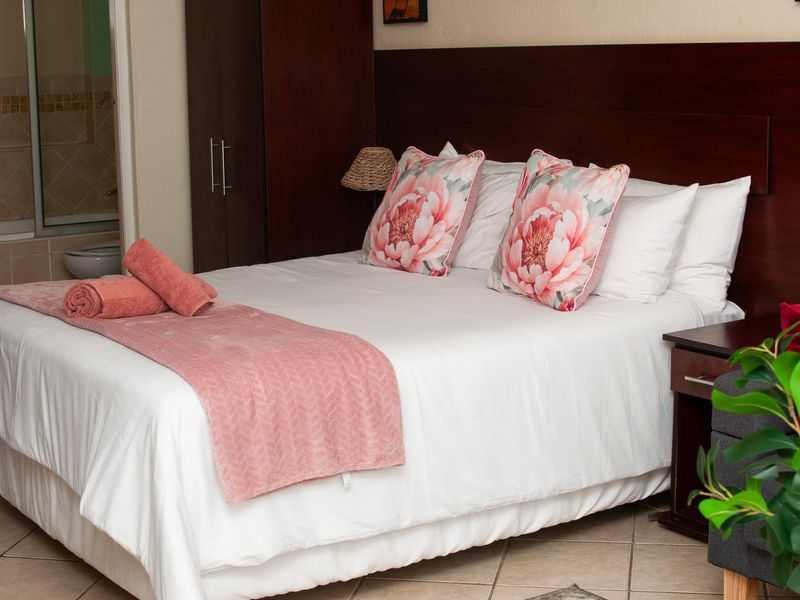 A bedroom featuring tiled flooring, a built-in wardrobe, and direct access to an en-suite bathroom.