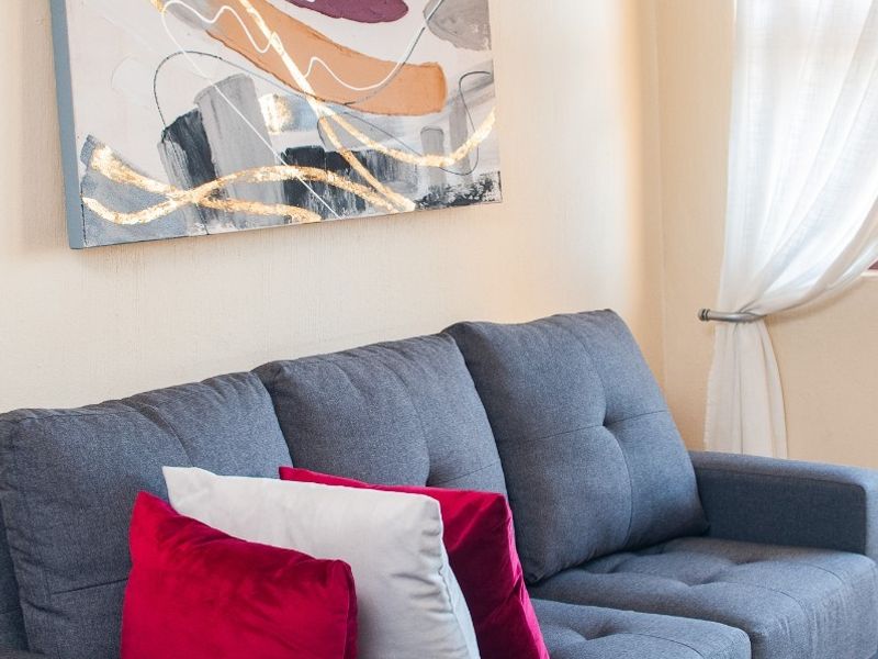 A cozy living room area featuring neutral wall tones, tiled flooring, and a window fitted with a curtain rod.